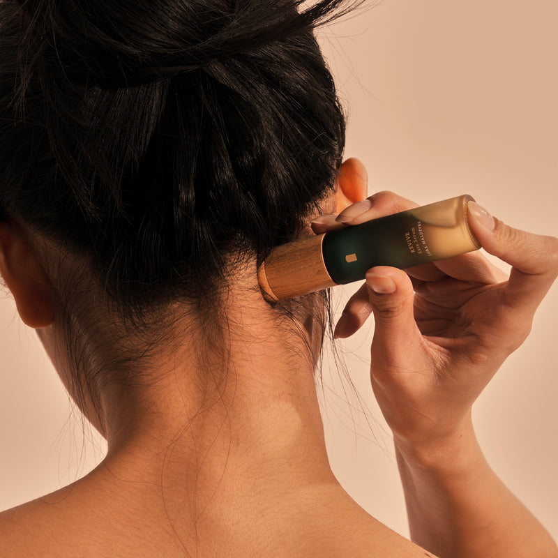 Close-up of the back of the neck and upper shoulders being massaged with the Revive Exta Serum wooden cap massager