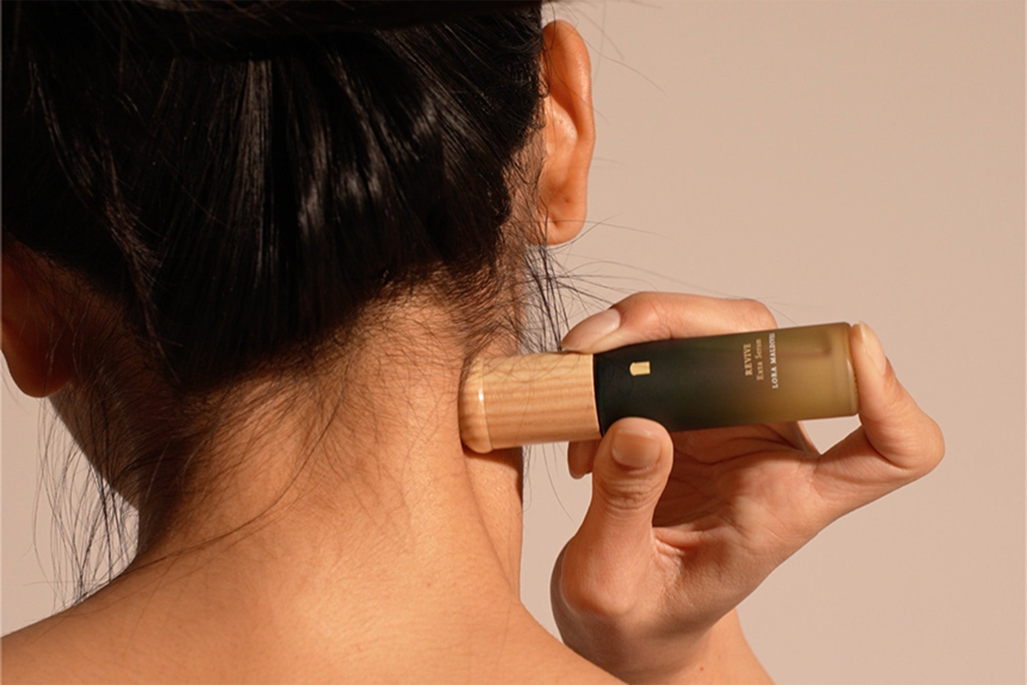 Signature woodcap massager rolling along neck line — close-up of ash wood grain texture, natural and tactile