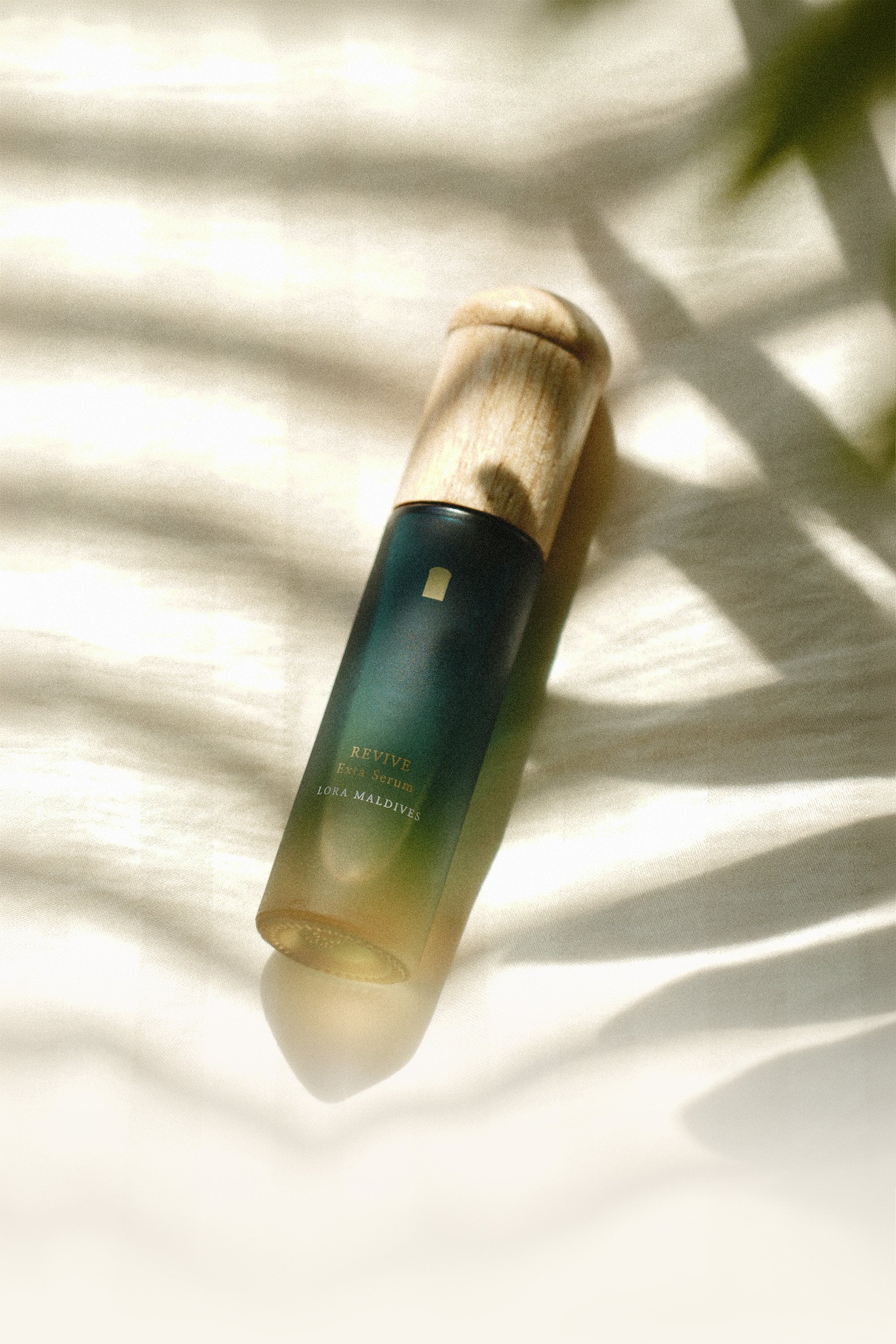 Revive Exta Serum — light and shadow crossing over the product, lying on its side, clean and beautiful product shot