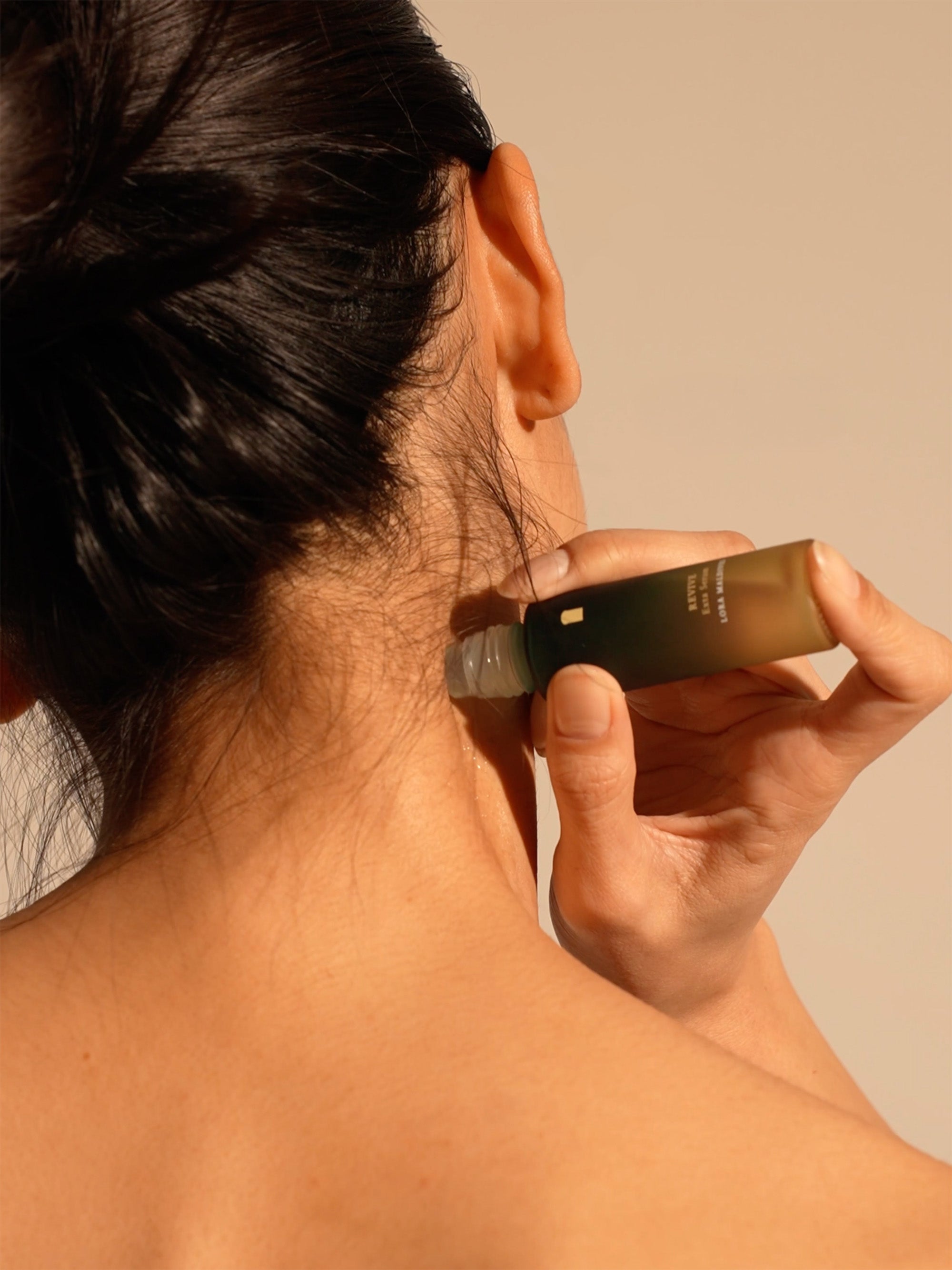 Step 1: Apply — rolling the serum onto the back of neck and behind ears, close-up
