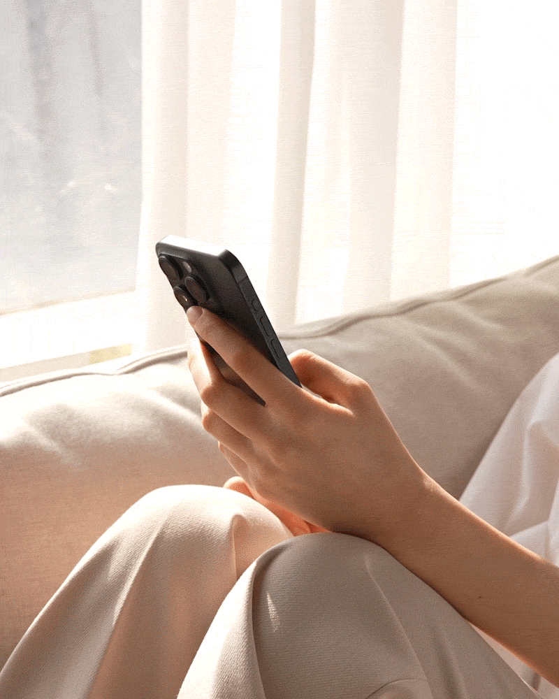 Person on sofa looking down at smartphone, head bent forward — neck tension